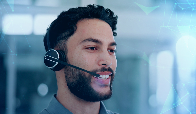 A man with a headset on, talking on the phone, in a call centre
