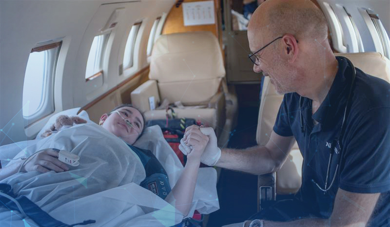 A customer on a stretcher in an air ambulance, holding the doctors hand. 