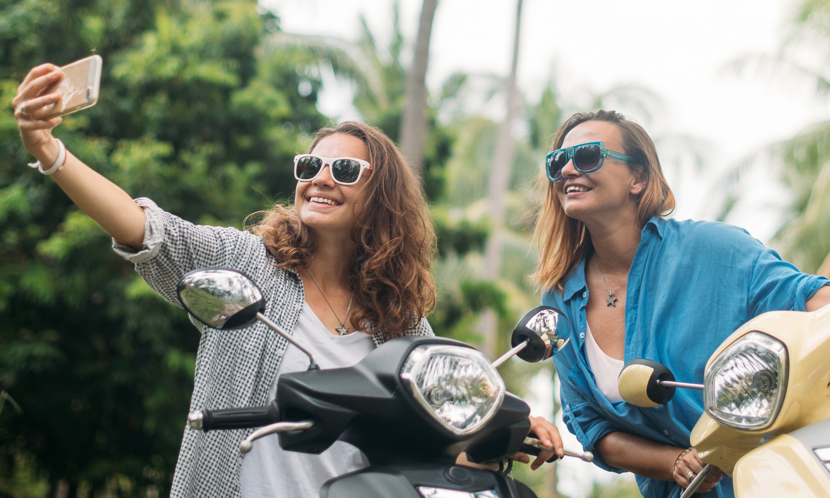 Deux jeunes filles en vacances se prennent en photo sur un scooter